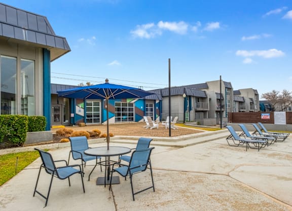 A patio with chairs and a table in front of a building.