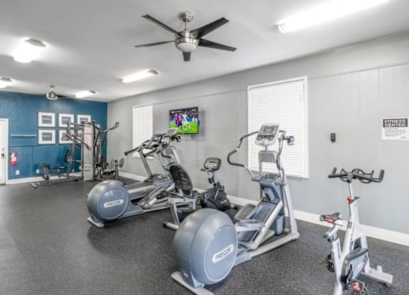 A spacious gym with a variety of exercise equipment including treadmills, stationary bikes, and weight machines.