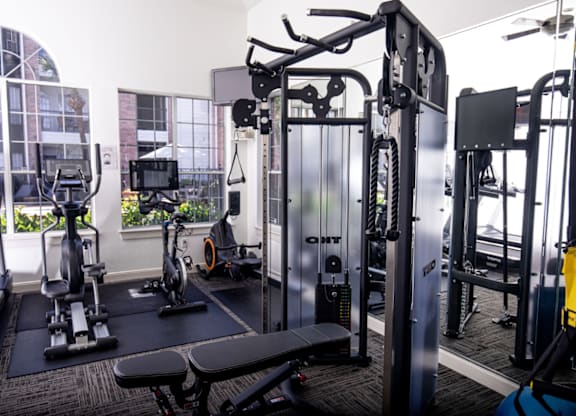 Gym with a variety of equipment including a treadmill, stationary bike, and weight machines at Whitney at the Heights, Texas