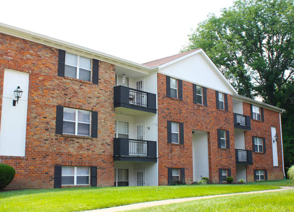 a brick and white building with a grass yard  at Four Worlds Apartments, Cincinnati