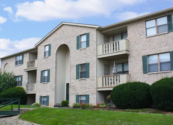 an exterior view of a brick apartment building with green grass and shrubs  at Four Worlds Apartments, Ohio, 45231