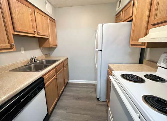 A kitchen with a white fridge, black stove, and wooden cabinets.
