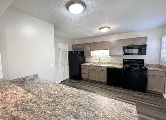 an empty kitchen with black appliances and a granite counter top at Revere Village Apartments, Centerville, 45458