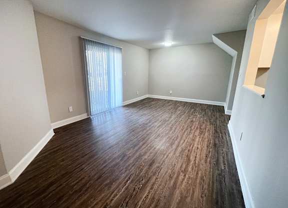 A room with wooden flooring and a window with blinds.