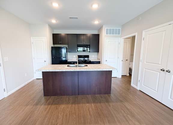 A kitchen with a dark brown island and white cabinets.