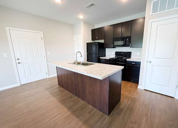 A kitchen with a white countertop and dark brown cabinets.