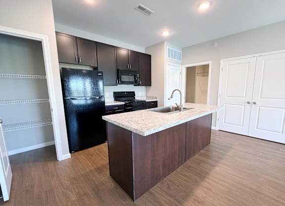A kitchen with a black refrigerator, microwave, and stove.