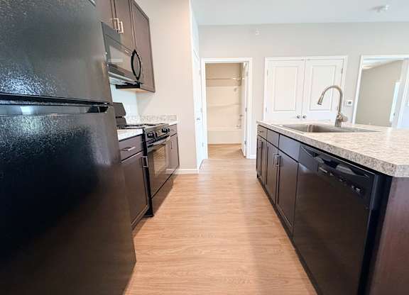A kitchen with black appliances and wooden floors.