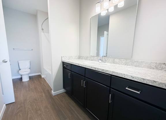 A bathroom with a toilet, sink, and mirror.