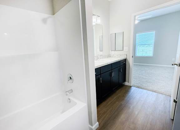 A white bathroom with a tub and a mirror.
