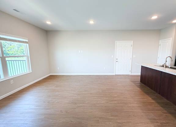 A room with wooden flooring and a window on the left side.