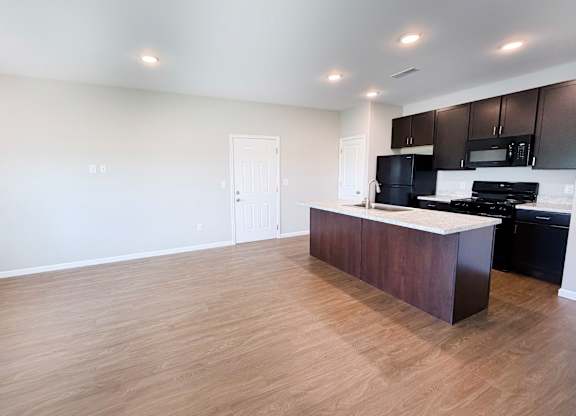 A kitchen with a black stove top oven and white walls.