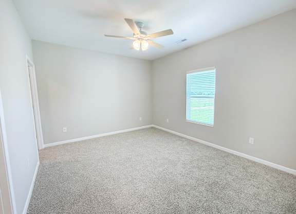 A room with a ceiling fan and carpeted floor.