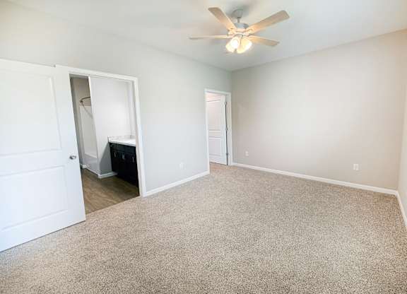 A room with a ceiling fan and carpeted floor.