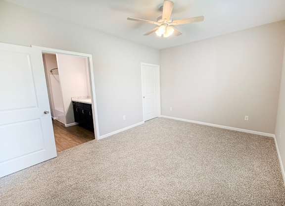 A room with a ceiling fan and carpeted floor.