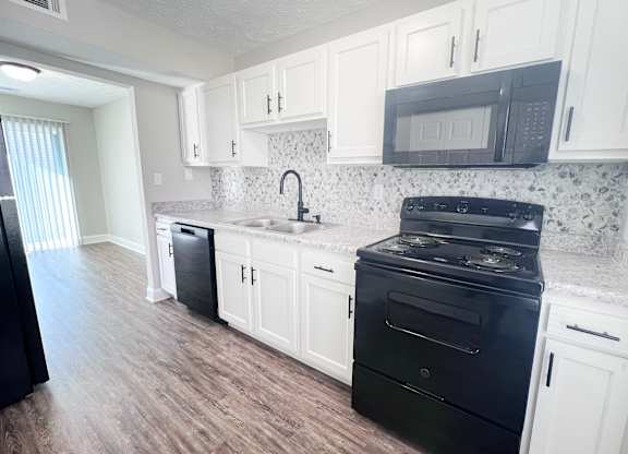 A kitchen with black appliances and white cabinets.