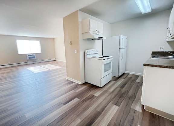 A kitchen with white appliances and wooden floors.