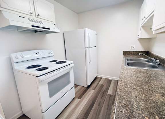 A kitchen with a white stove, white cabinets, and a white refrigerator.