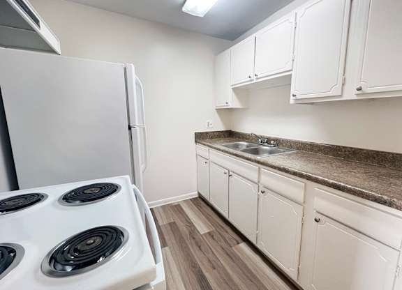 A kitchen with a white stove and cabinets.
