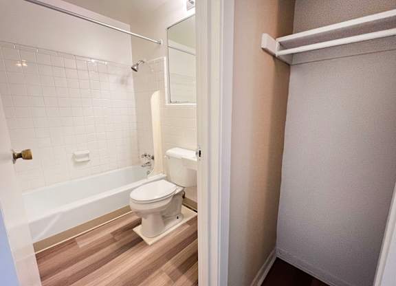 A white toilet in a small bathroom with a white bathtub and a white door.