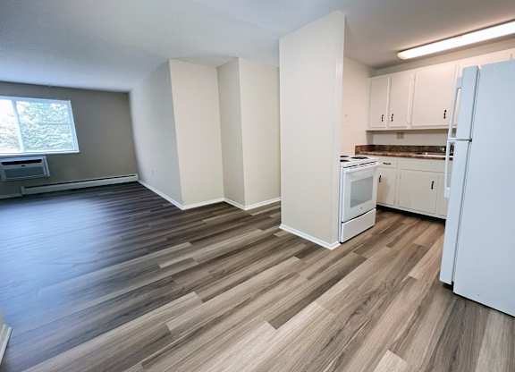 A kitchen with white appliances and wooden floors.