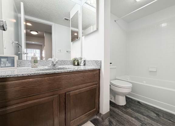 A bathroom with a wooden vanity and a white toilet.