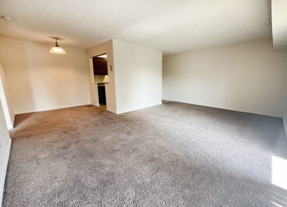 an empty living room with carpet and white walls at Four Worlds Apartments, Ohio
