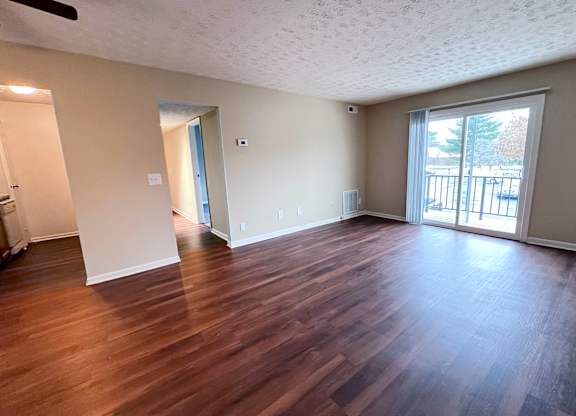 A room with wooden flooring and a sliding glass door.