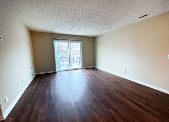 A room with wooden floors and a sliding glass door.