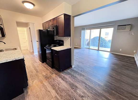 A kitchen with dark wood cabinets and a black fridge.