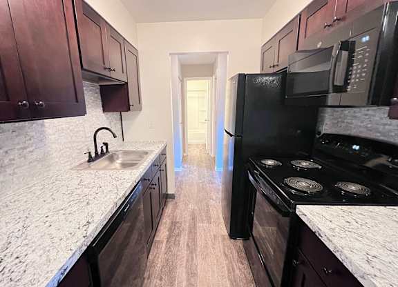A kitchen with dark wood cabinets and a black stove top oven.