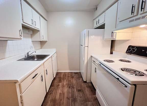 A kitchen with white cabinets and a white stove top oven.