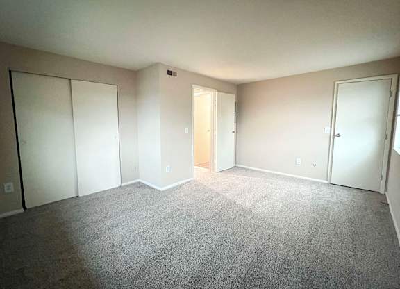 A room with carpeted floor and three doors.