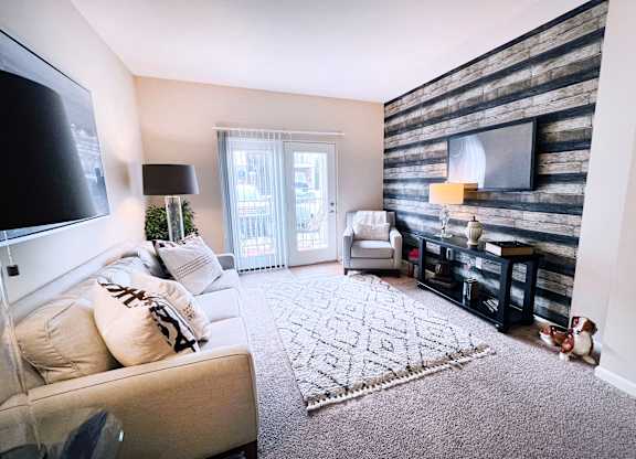 A living room with a couch, a rug, a TV, and a wooden wall.
