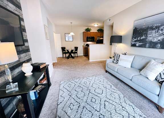 A living room with a grey couch, a patterned rug, and a black and white photo on the wall.