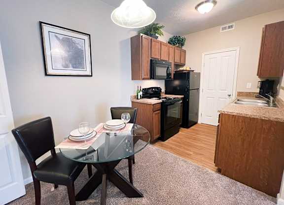A dining table with a glass top and four chairs around it.