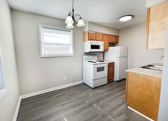 A kitchen with white appliances and wooden cabinets.
