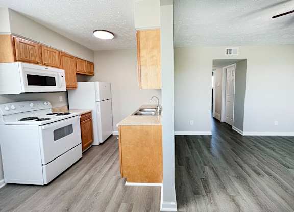 A kitchen with white appliances and wooden cabinets.