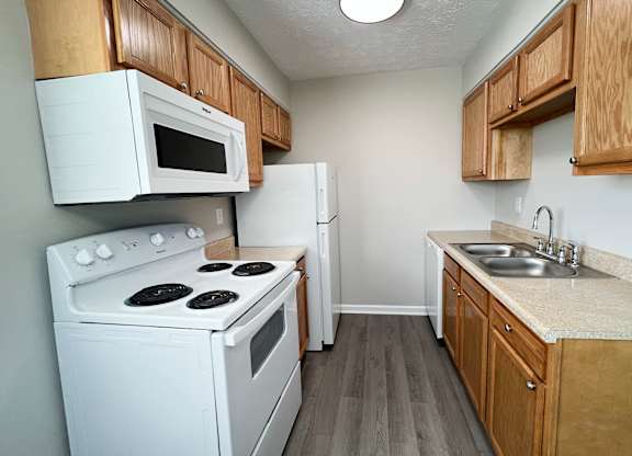 A kitchen with white appliances and wooden cabinets.
