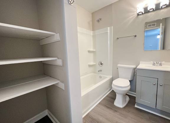 A white toilet sits in a bathroom next to a sink and a bathtub.