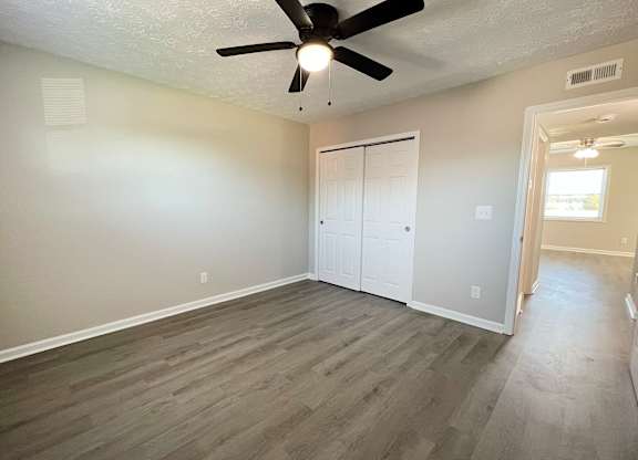 A room with a ceiling fan and a door.