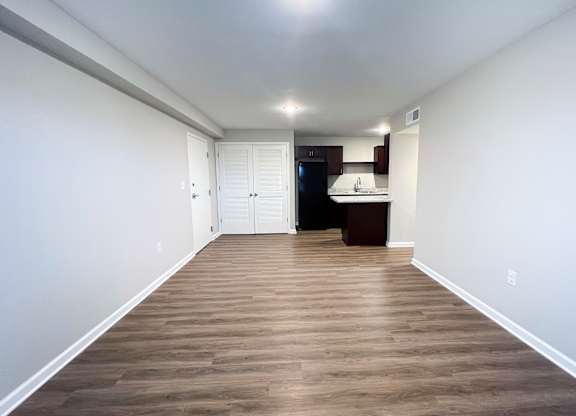 A long, narrow room with wood flooring and white walls.