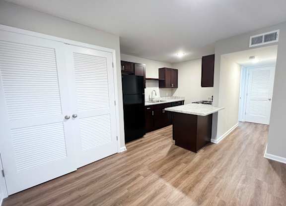 A kitchen with white cabinets and a black fridge.