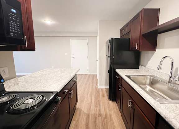 A kitchen with black appliances and wooden cabinets.
