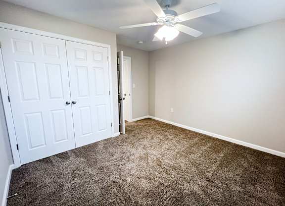 A room with a ceiling fan and carpeted floor.