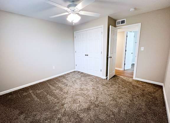 A room with a carpeted floor and a ceiling fan.