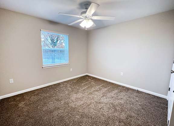 A room with a ceiling fan and carpeted floor.