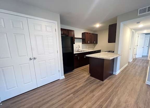 A kitchen with white cabinets and a wooden floor.