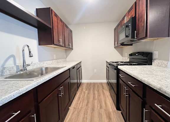A kitchen with dark wood cabinets and a granite countertop.