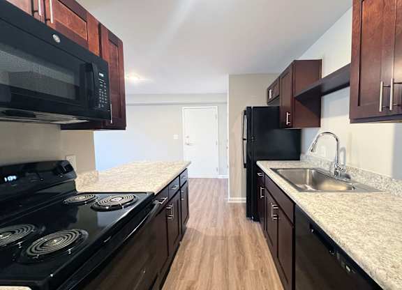 A kitchen with black appliances and wooden cabinets.